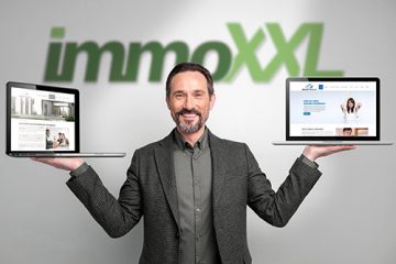 Mann hlt zwei Laptops mit immoXXL-Webseiten hoch